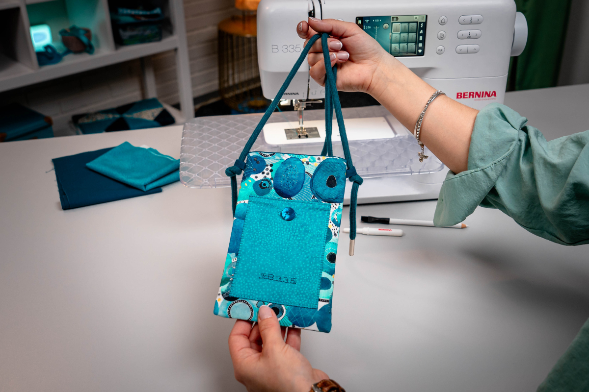 Blue bag with cord, part of a smartphone is looking out of the bag