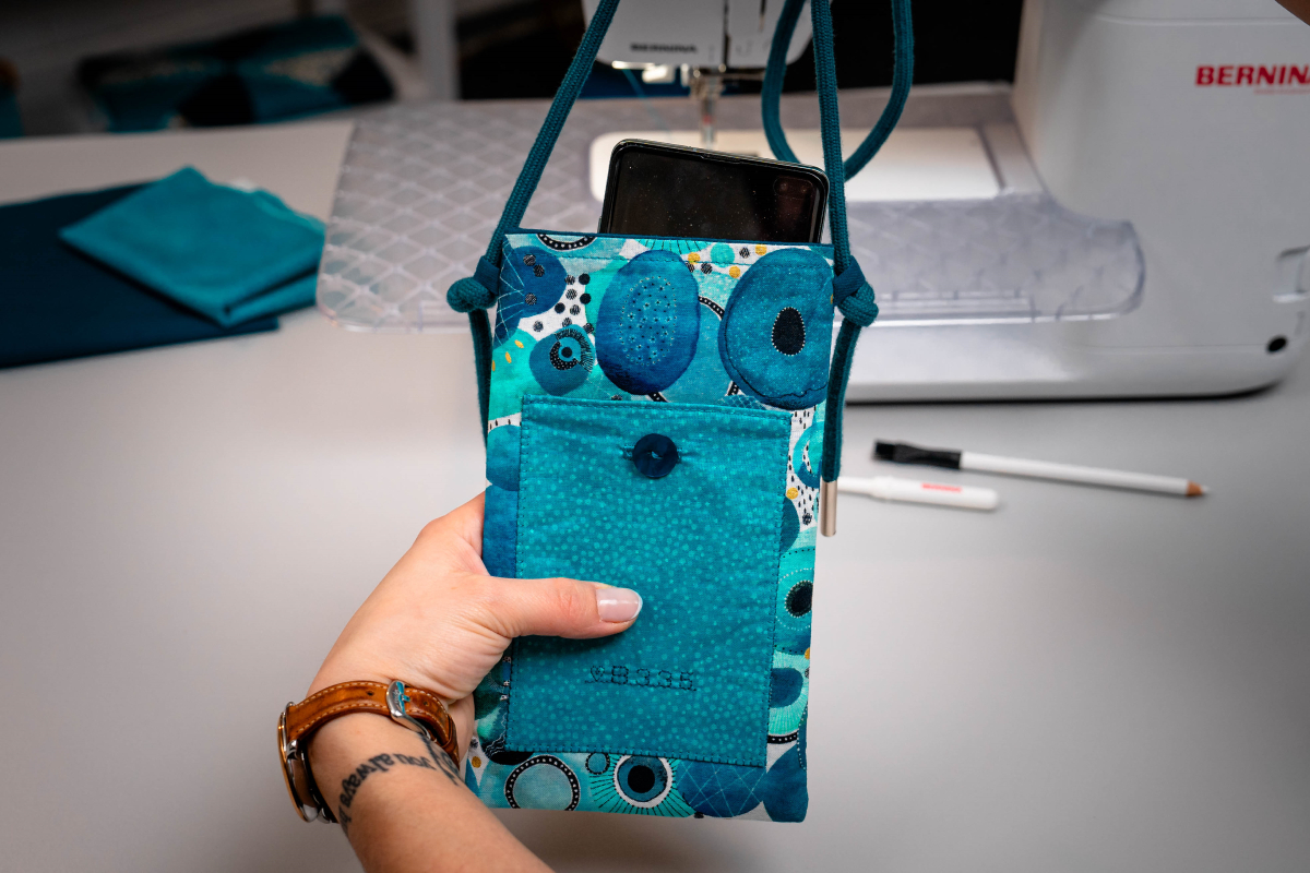 Blue bag with cord, part of a smartphone is looking out of the bag