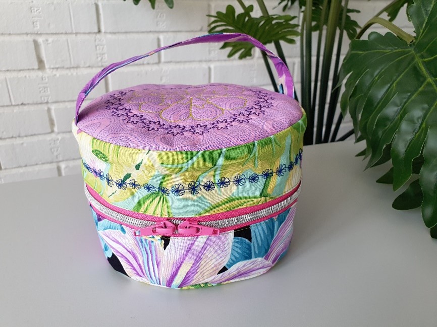 Colorful round bag with zipper in the middle of the side and handle.