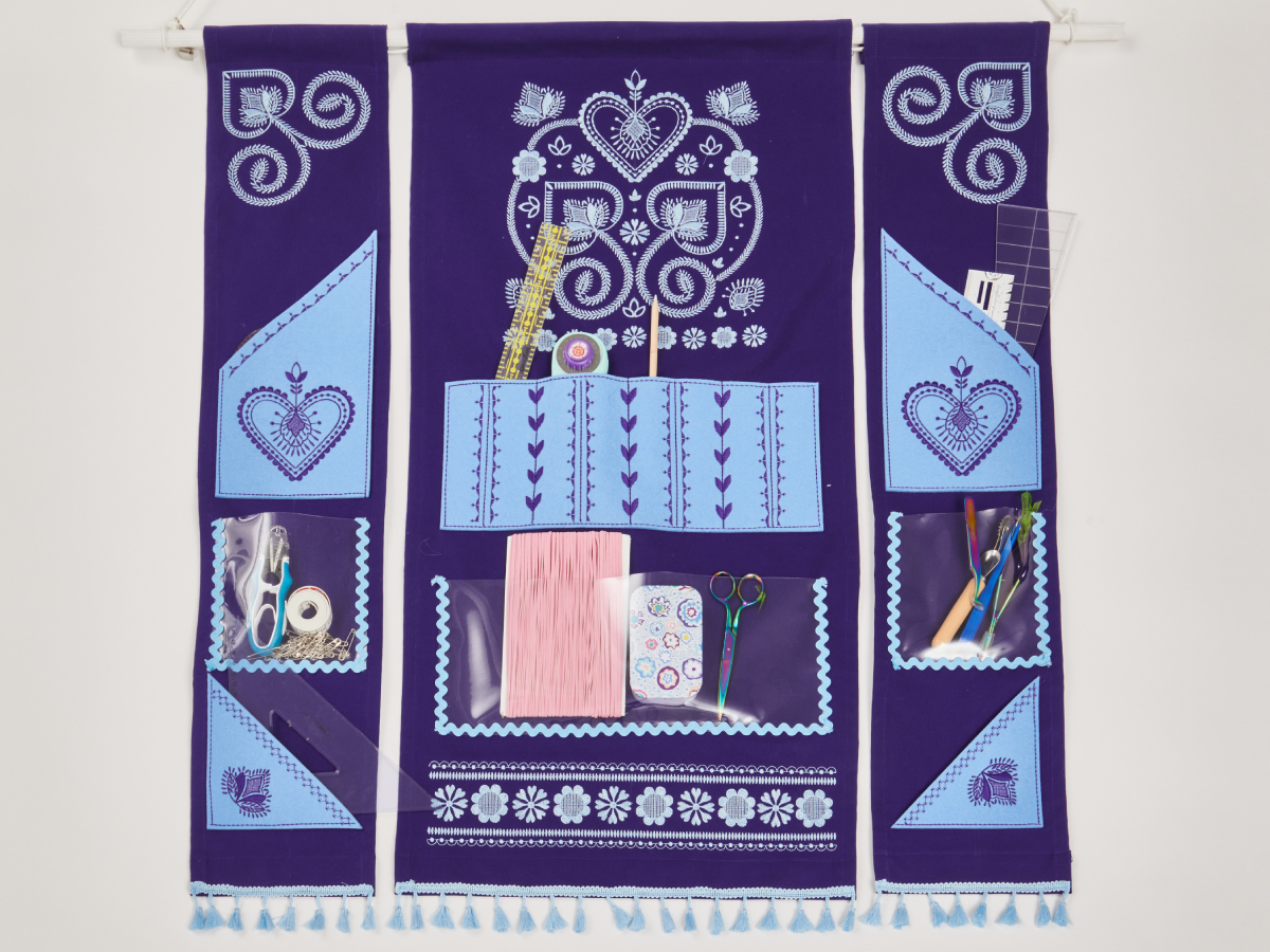 The wall organizer is made from 3 fabric strips: 2 small ones to the left and right, the central one is bigger. Its made from dark blue fabric with bright blue or transparent elements with embroidery 